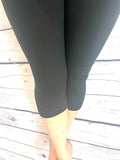 Woman wearing plus size black yoga band capri leggings